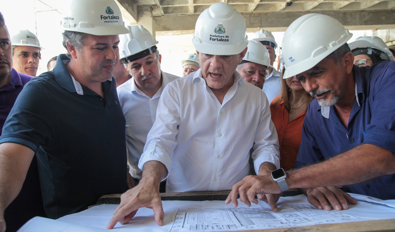 prefeito observa a planta da escola em construção